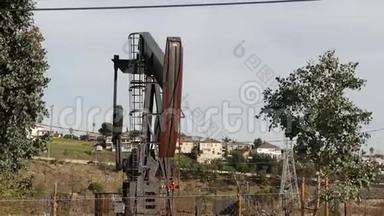 工业城市景观。 洛杉矶的拉布雷亚·英格尔伍德。 井泵千斤顶在栅栏后面工作。 钻机